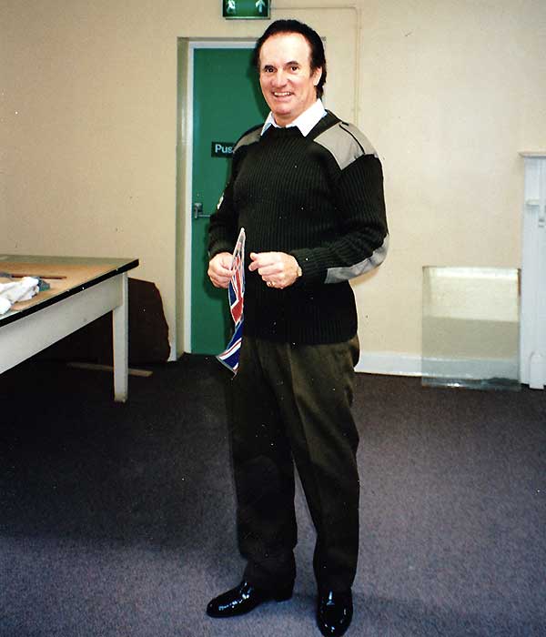 sean glenn acting in full character dressed in army clothing and holding a united kingdom flag