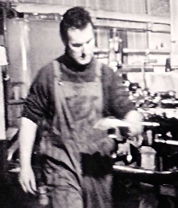 close up of sheffield actor sean glenn in machine engineering clothing including pocketed dungarees working in a machine shop